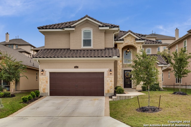 mediterranean / spanish home featuring a garage and a front lawn