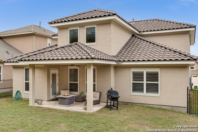 rear view of house with a patio, a lawn, and ceiling fan