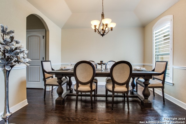 dining space featuring vaulted ceiling, a chandelier, and dark wood-type flooring