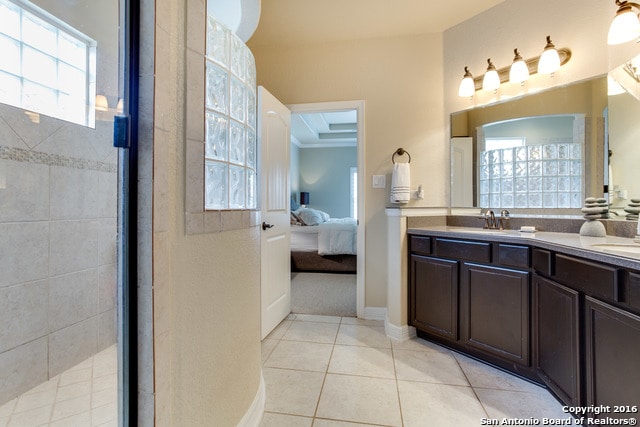 bathroom with a tile shower, tile patterned flooring, and vanity