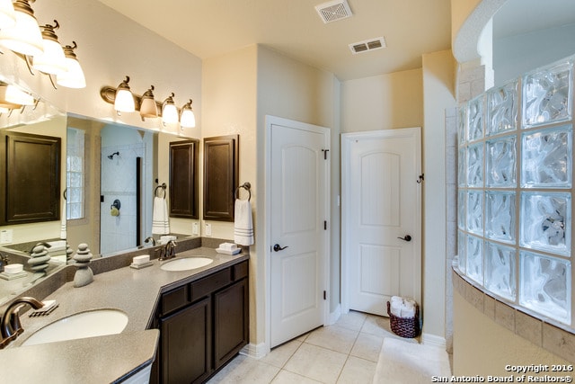 bathroom featuring tiled shower, vanity, and tile patterned floors