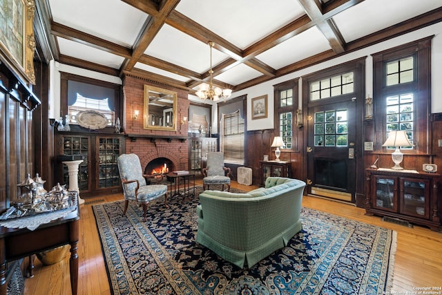 living room featuring coffered ceiling, a fireplace, beam ceiling, hardwood / wood-style floors, and a notable chandelier