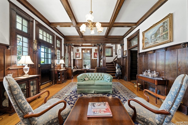 sitting room featuring light hardwood / wood-style floors, decorative columns, wooden walls, and a chandelier