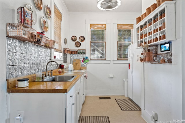 kitchen featuring crown molding, white cabinets, sink, and a wealth of natural light