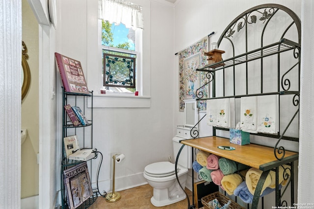 bathroom featuring tile patterned flooring, ornamental molding, and toilet