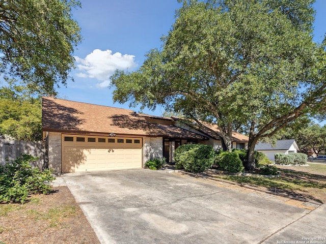 view of front facade featuring an attached garage, driveway, and fence