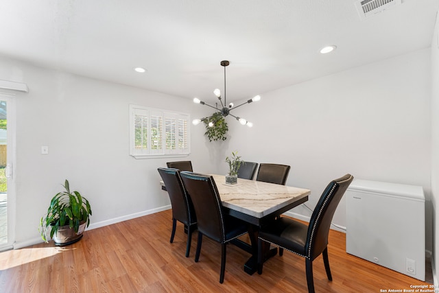 dining space featuring light hardwood / wood-style floors and a notable chandelier