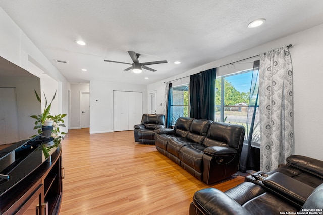 living room with light hardwood / wood-style flooring, ceiling fan, and a textured ceiling