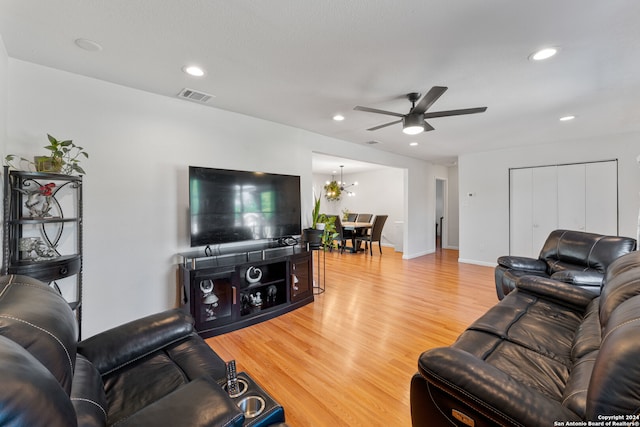 living room with hardwood / wood-style flooring and ceiling fan with notable chandelier