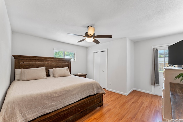 bedroom with ceiling fan, light hardwood / wood-style flooring, a closet, and multiple windows