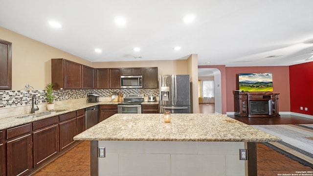 kitchen featuring light stone countertops, stainless steel appliances, sink, and a center island