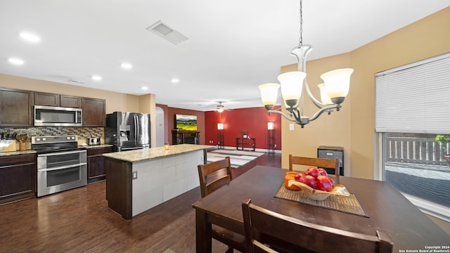 kitchen with dark brown cabinets, decorative light fixtures, appliances with stainless steel finishes, ceiling fan with notable chandelier, and dark hardwood / wood-style flooring