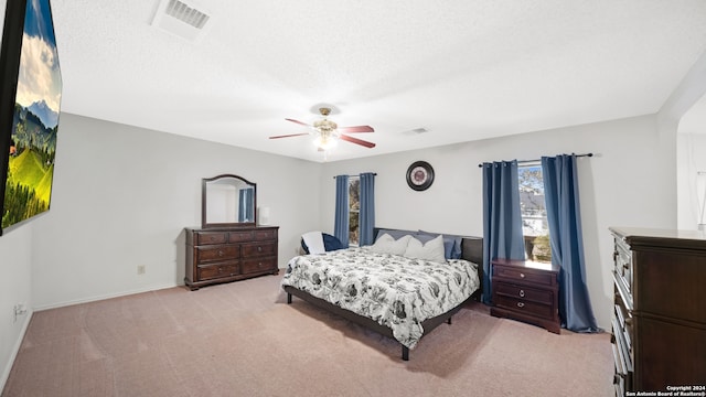 bedroom featuring light colored carpet, a textured ceiling, and ceiling fan