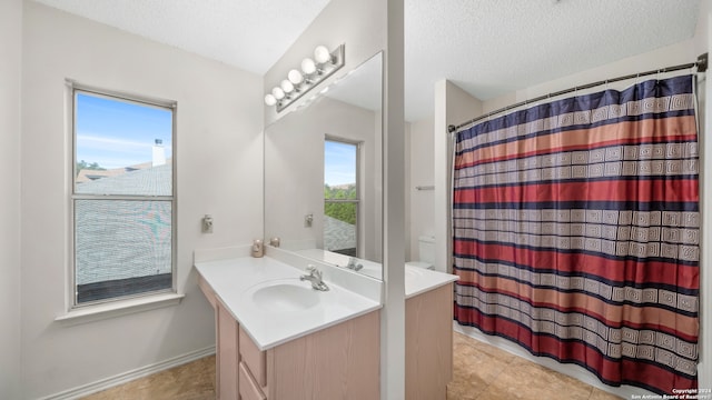 bathroom with tile patterned flooring, toilet, vanity, and a textured ceiling