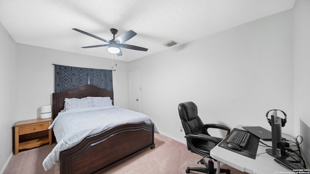 bedroom featuring a textured ceiling, ceiling fan, and light colored carpet