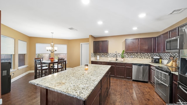 kitchen featuring decorative backsplash, a center island, stainless steel appliances, dark wood-type flooring, and hanging light fixtures