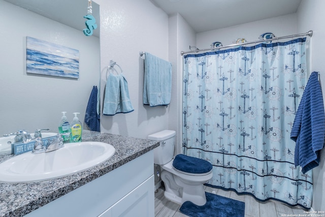 bathroom with walk in shower, vanity, and toilet