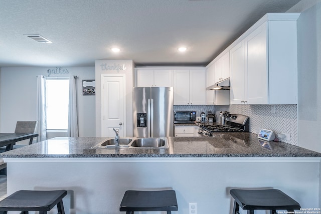 kitchen with a breakfast bar, tasteful backsplash, white cabinetry, kitchen peninsula, and appliances with stainless steel finishes