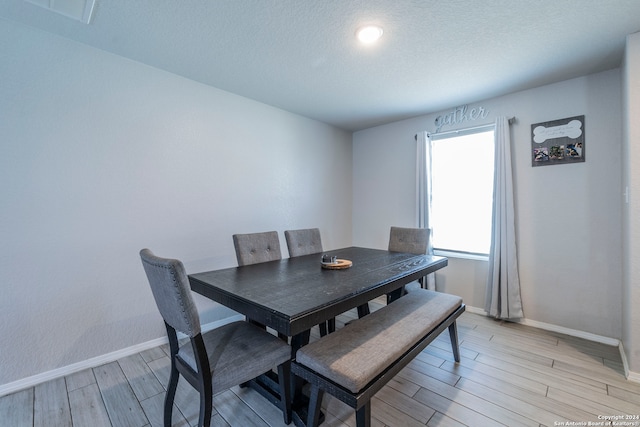 dining room featuring light wood-type flooring and a textured ceiling