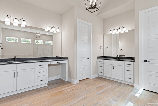 bathroom with wood-type flooring, vanity, and an inviting chandelier