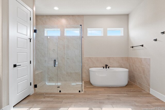 bathroom with tile walls and shower with separate bathtub