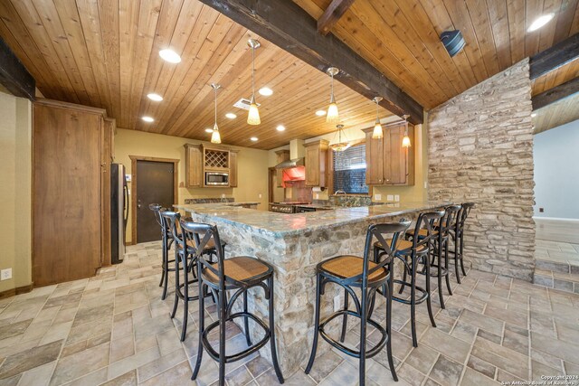 kitchen with beamed ceiling, kitchen peninsula, decorative light fixtures, stone counters, and stainless steel appliances