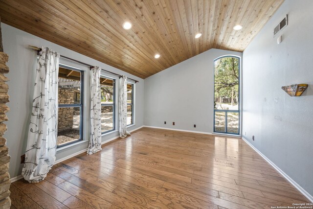 empty room with a healthy amount of sunlight, lofted ceiling, and light hardwood / wood-style flooring