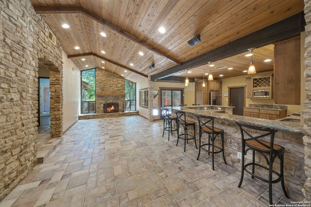 kitchen featuring kitchen peninsula, stone counters, high vaulted ceiling, decorative light fixtures, and wooden ceiling