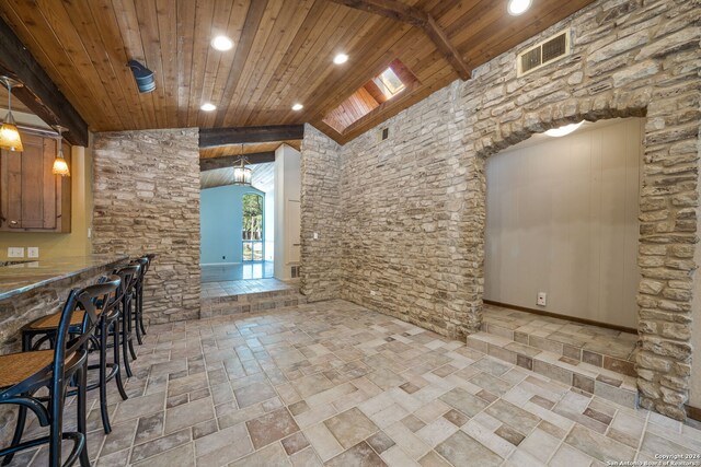 interior space featuring a skylight, hanging light fixtures, beam ceiling, high vaulted ceiling, and wooden ceiling