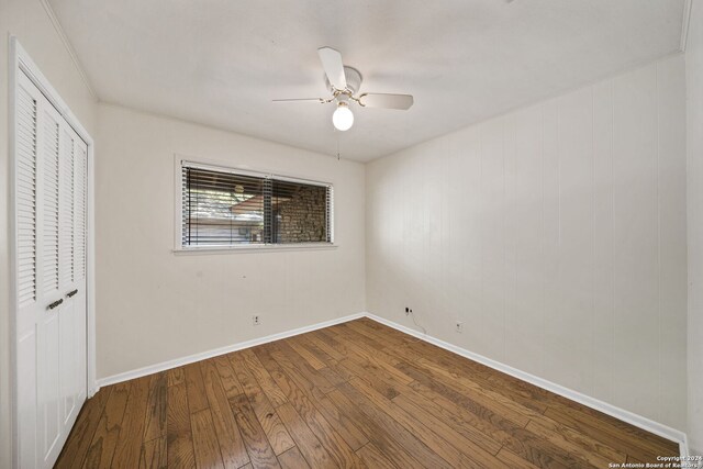 unfurnished bedroom featuring ceiling fan, a closet, hardwood / wood-style floors, and crown molding