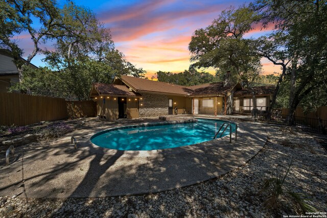 pool at dusk featuring a patio