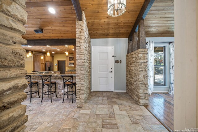 interior space featuring beamed ceiling, light wood-type flooring, a high ceiling, and wooden ceiling