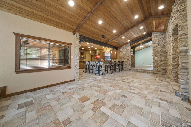 interior space with wooden ceiling, vaulted ceiling with beams, a breakfast bar area, and hanging light fixtures