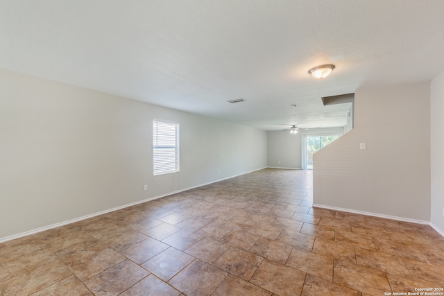 unfurnished room with ceiling fan and a textured ceiling