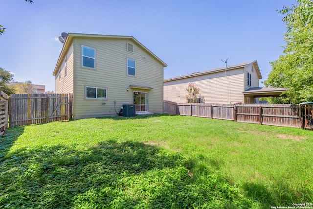 rear view of property with a yard and central AC unit