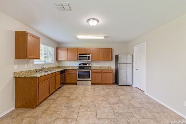 kitchen featuring light stone countertops, stainless steel appliances, and sink