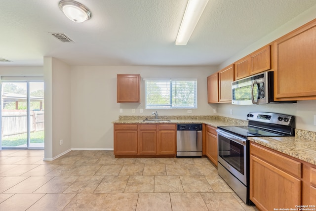 kitchen featuring light stone countertops, appliances with stainless steel finishes, plenty of natural light, and sink