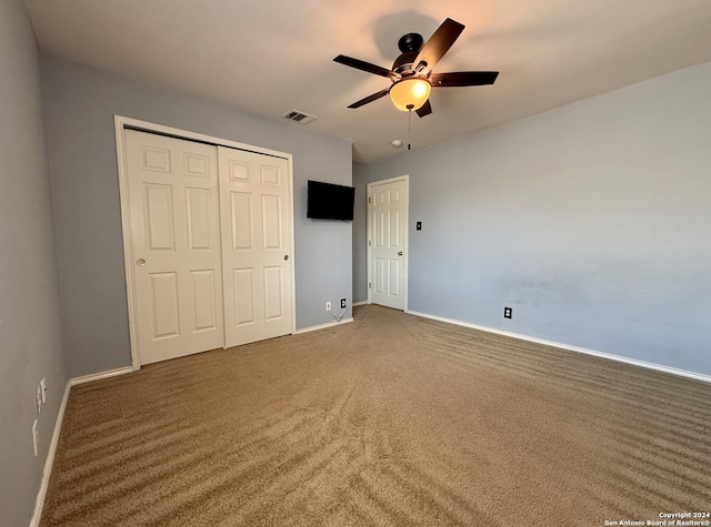 unfurnished bedroom featuring ceiling fan, a closet, and dark colored carpet