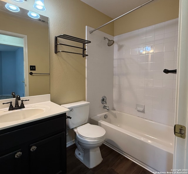 full bathroom featuring tiled shower / bath, hardwood / wood-style flooring, vanity, and toilet