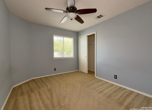 unfurnished bedroom featuring ceiling fan, light colored carpet, and a closet