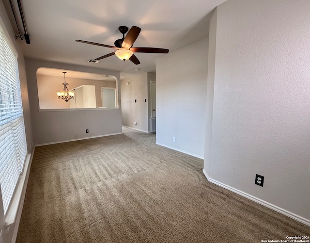 spare room with ceiling fan with notable chandelier, carpet flooring, and a wealth of natural light