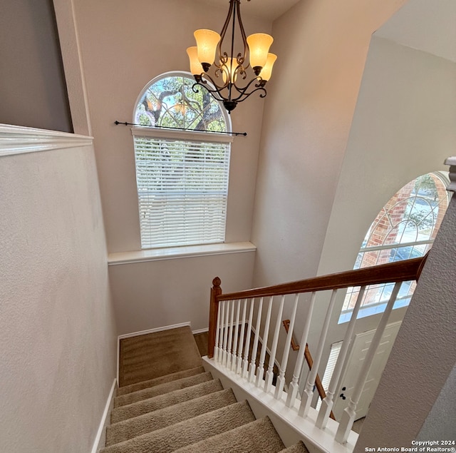 stairs featuring a notable chandelier