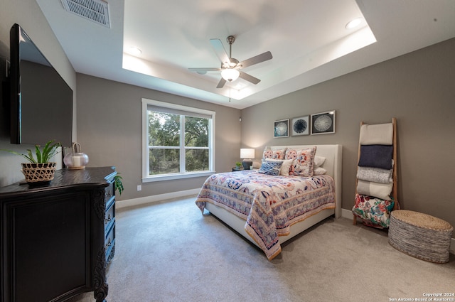 bedroom featuring ceiling fan, a raised ceiling, and light colored carpet