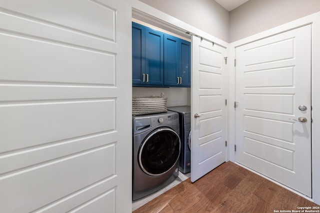 laundry room featuring cabinets, dark wood-type flooring, and washing machine and dryer