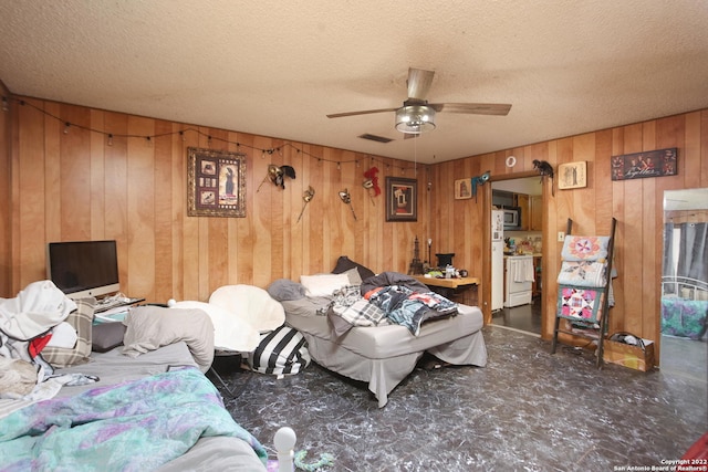 bedroom with a textured ceiling, wooden walls, and ceiling fan