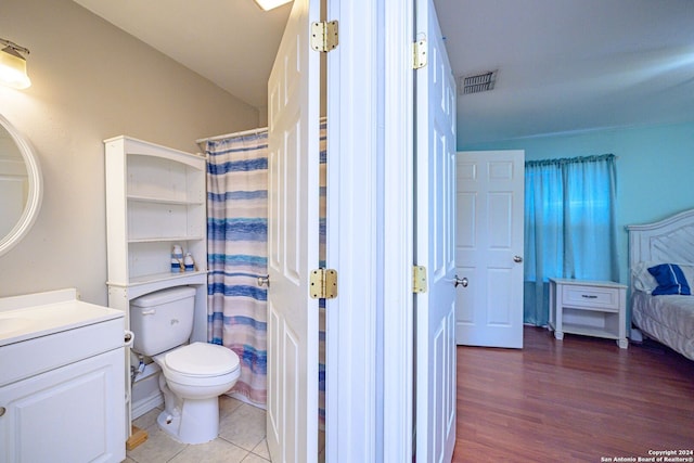 bathroom with wood-type flooring, vanity, toilet, and vaulted ceiling