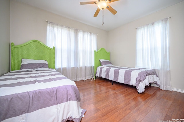 bedroom featuring multiple windows, wood-type flooring, and ceiling fan