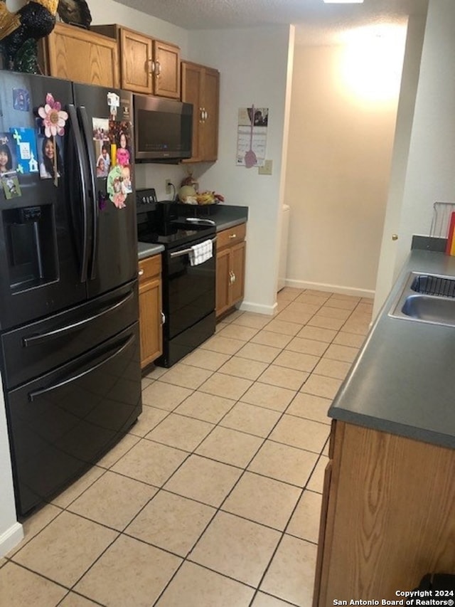 kitchen with light tile patterned flooring, sink, and black appliances