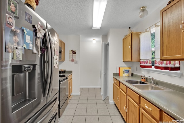 kitchen featuring light tile patterned floors, a textured ceiling, stainless steel appliances, and sink