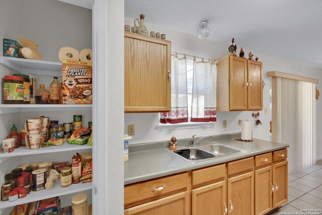 kitchen featuring light brown cabinetry, a textured ceiling, light tile patterned floors, and sink